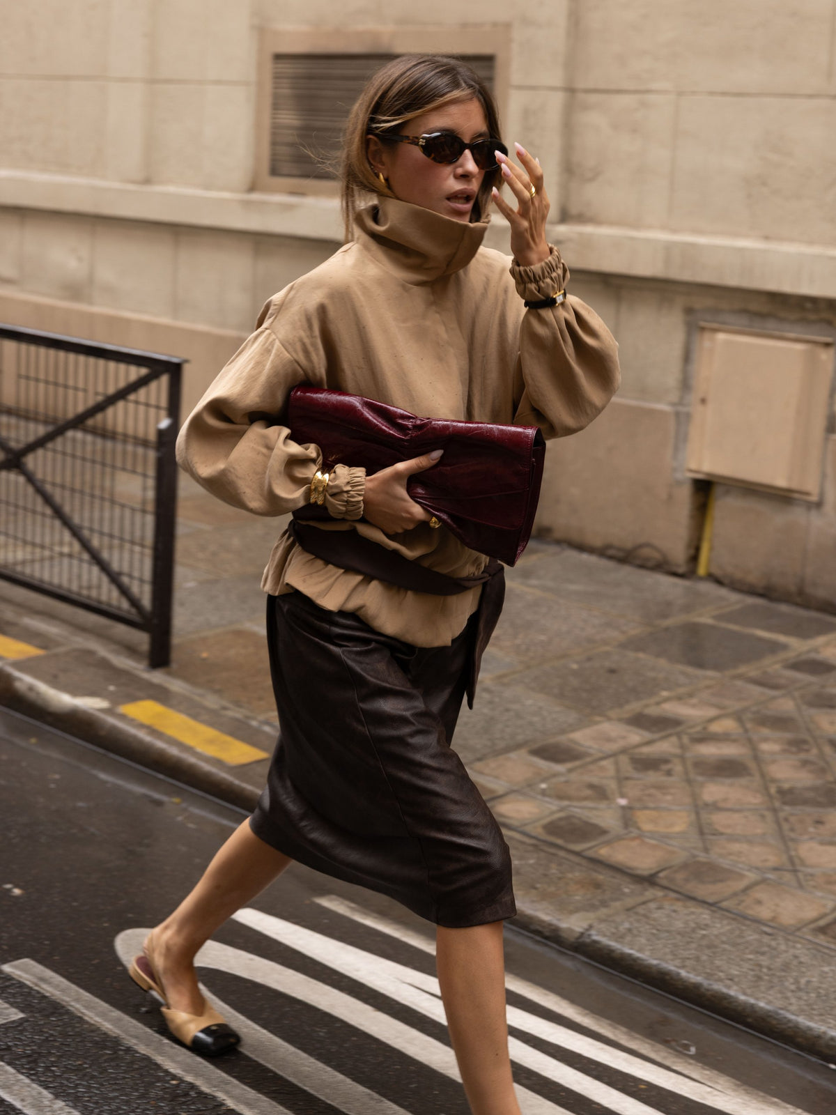 Sasha walking a Paris street with a burgundy clutch